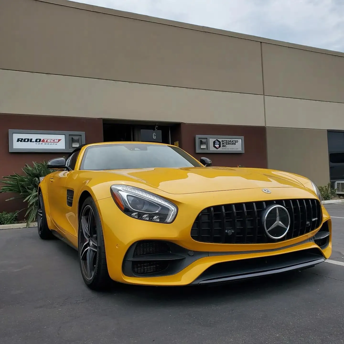 paint-1 Yellow Mercedes-Benz sports car parked in front of an industrial building with signage visible.